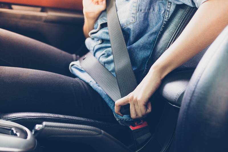 Photo of person putting on their seatbelt.