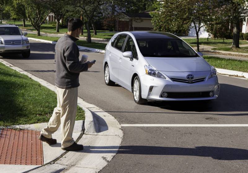 Photo of man crossing street with car close to him.