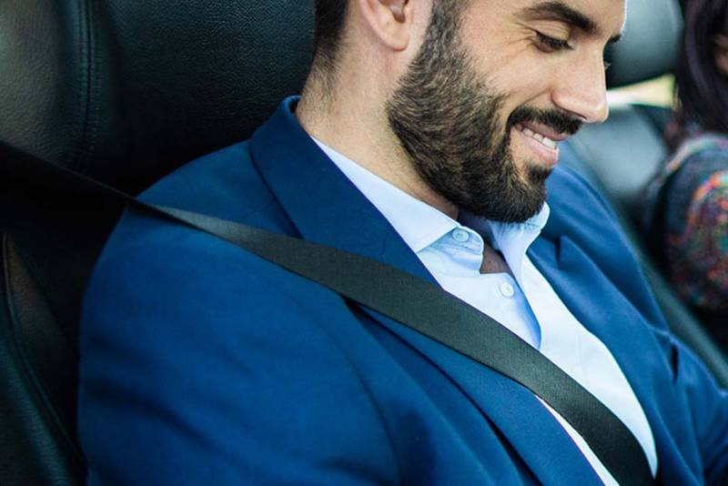 Man sitting in car wearing seatbelt.